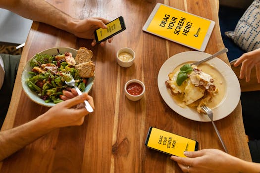 Group dining with electronic devices and fresh meals on a wooden table.