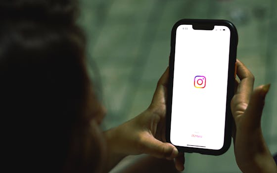 Close-up of a woman holding a smartphone displaying the Instagram app indoors.